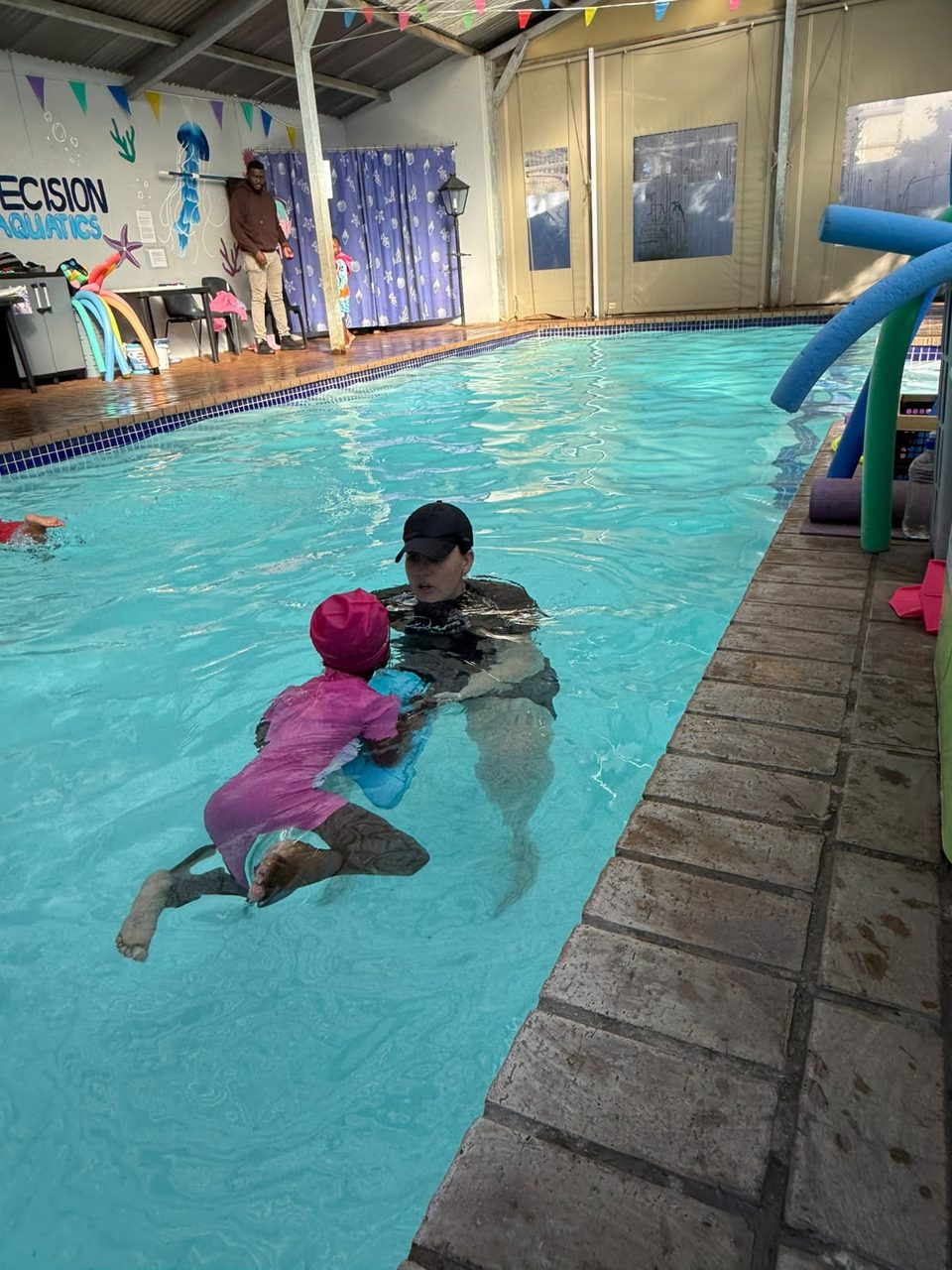 Precision Aquatics indoor pool with wall signage and colourful bunting