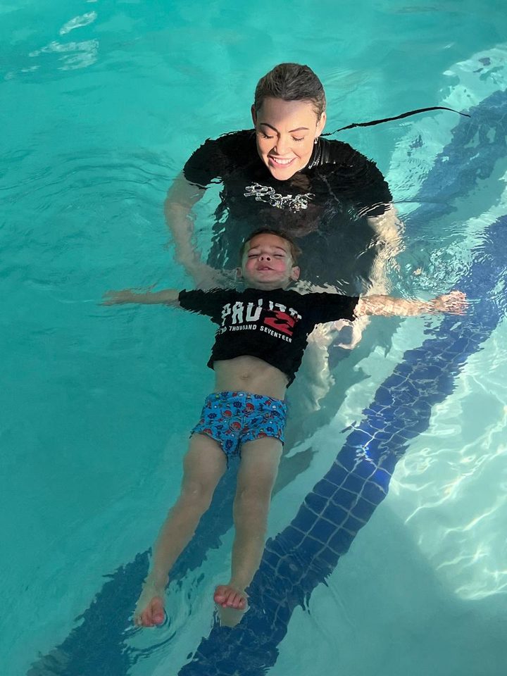 Child practising floating on their back with instructor support