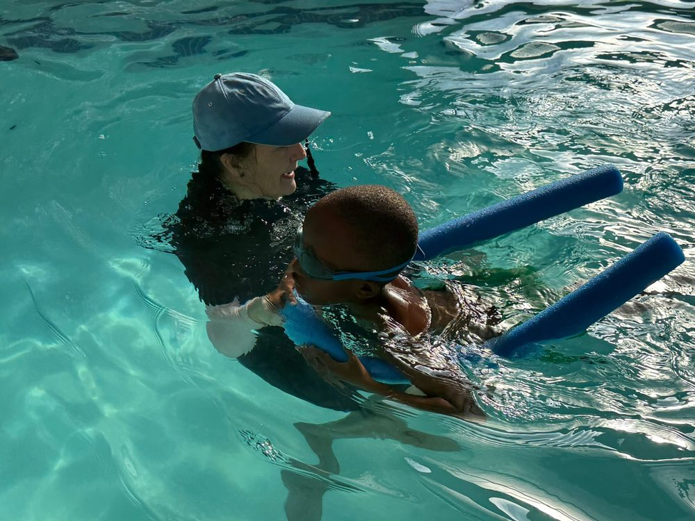 Instructor supporting a child using a pool noodle during a swimming lesson