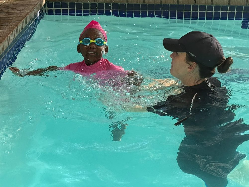 Instructor guiding a child through a swimming stroke