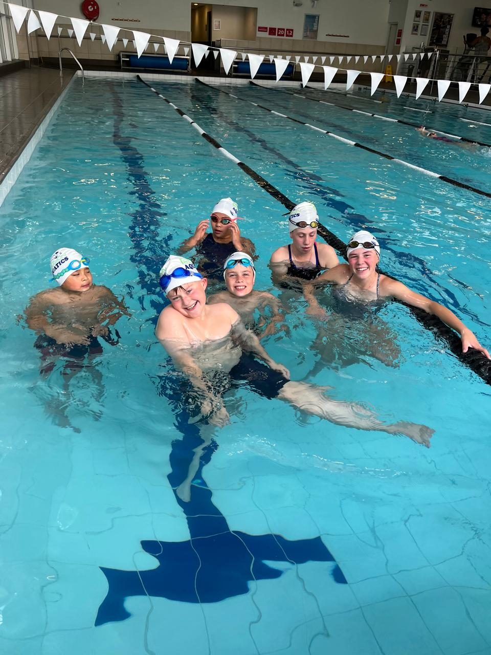 Precision Aquatics squad swimmers training in an indoor lap pool