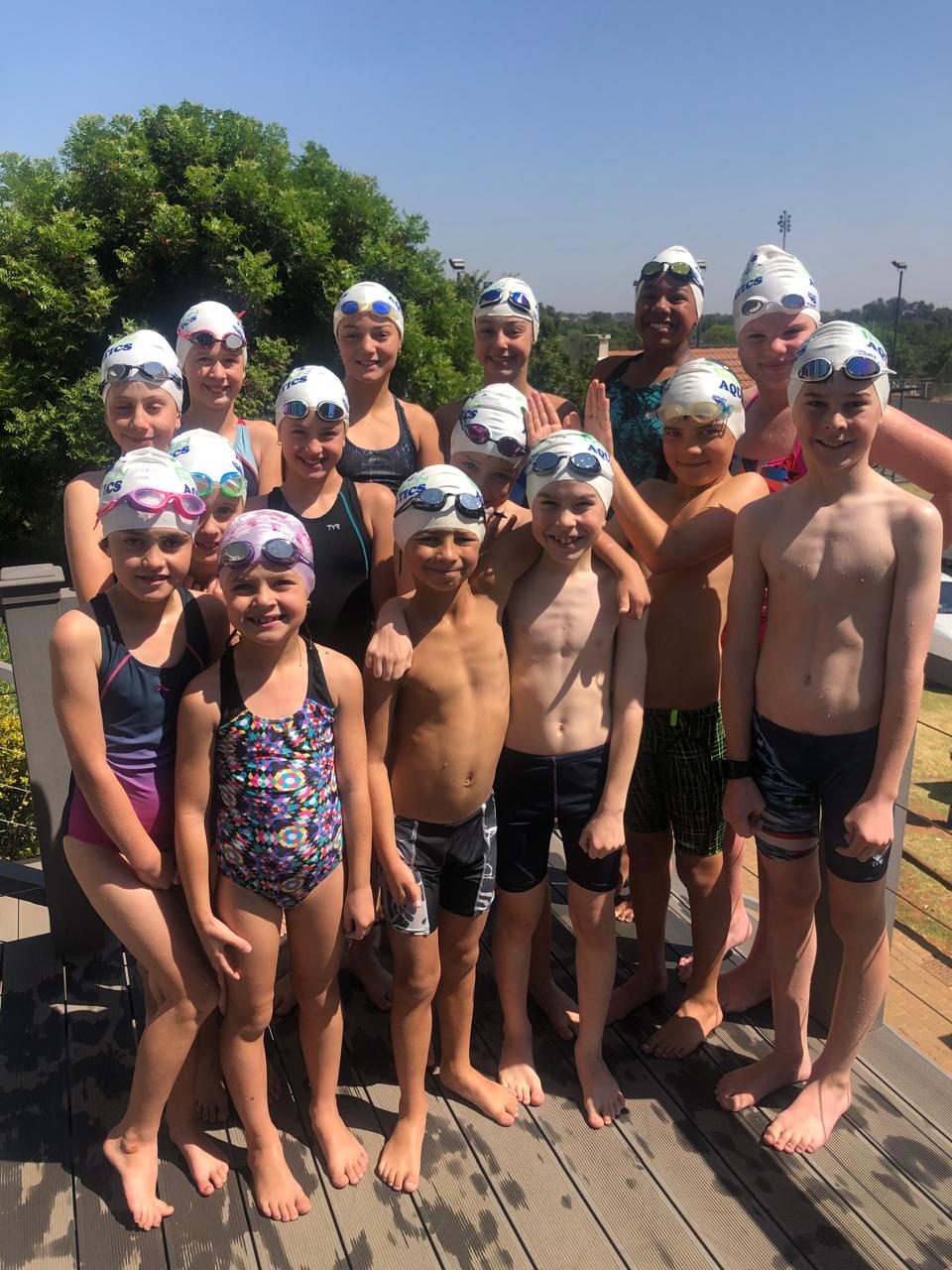 Precision Aquatics squad swimmers in branded caps, group photo